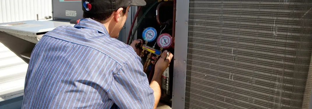 HVAC technician servicing a condenser unit in Marshall